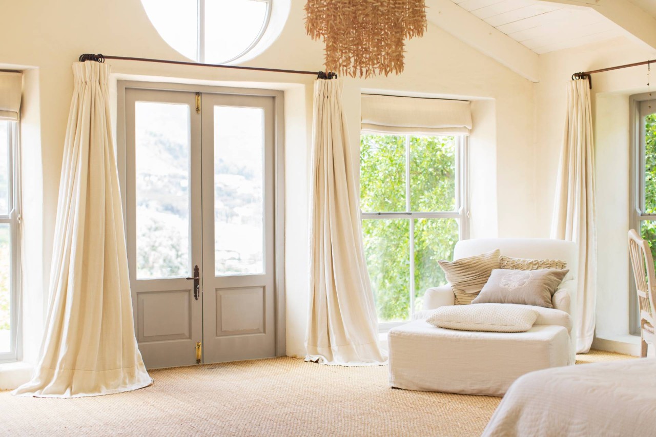 Flowing white window treatments set on either side of a gray set of French doors near Boynton Beach, FL