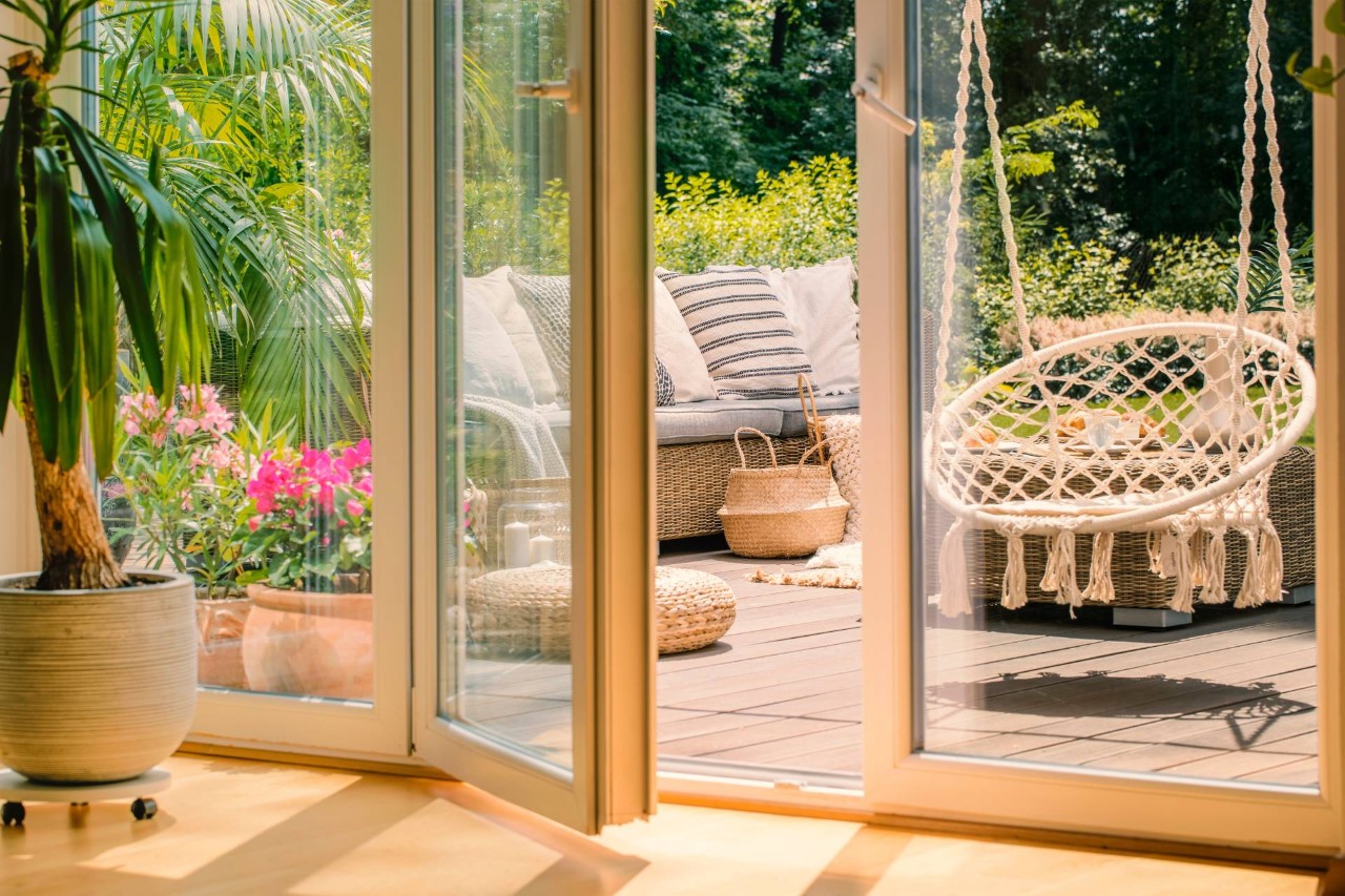 French doors leading outside to a patio with lots of greenery and boho chic-inspired outdoor furniture at  Enhancement Window Design near Boynton Beach, FL