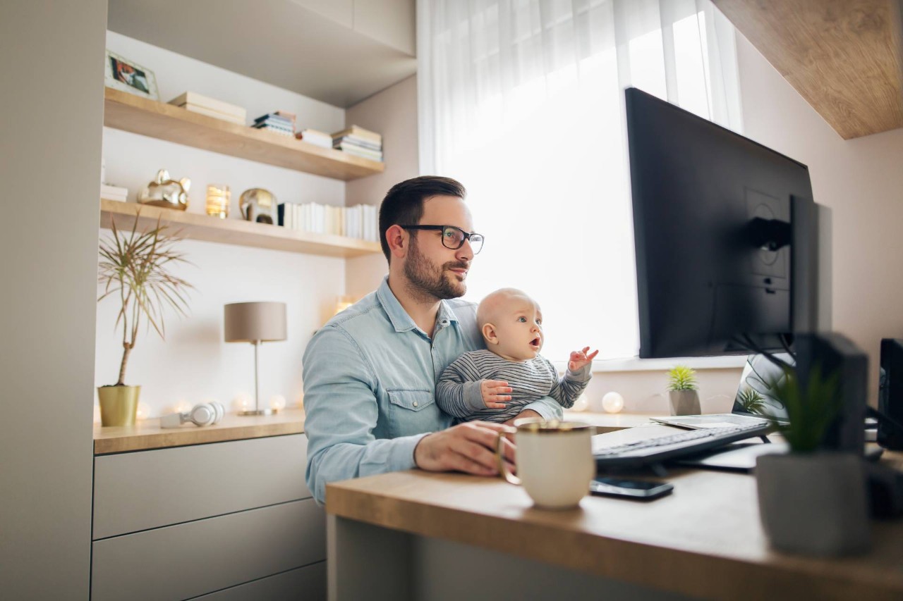 A father holding his child and working from home with sheer home office shades at Enhancement Window Design near Boynton Beach, (FL)